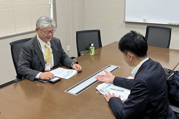 会議室で男性が向かい合って話している写真
